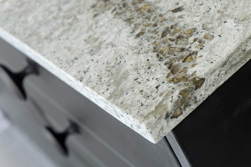 Close-up of a polished concrete countertop with embedded glass pieces, expertly finished for a textured and decorative edge above dark cabinetry—perfect for those seeking stone restoration NYC services.