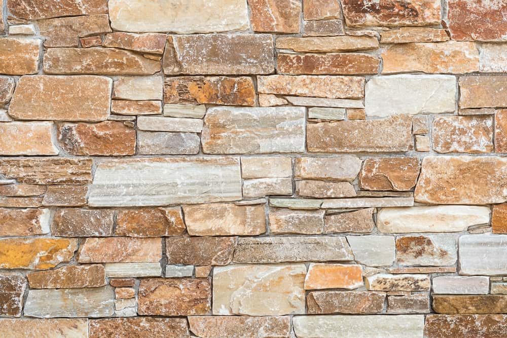 A close-up view of a wall made of irregularly shaped, multicolored stones in shades of brown, beige, and gray—perfect inspiration for stone restoration NYC specialists—stacked together with visible mortar lines.